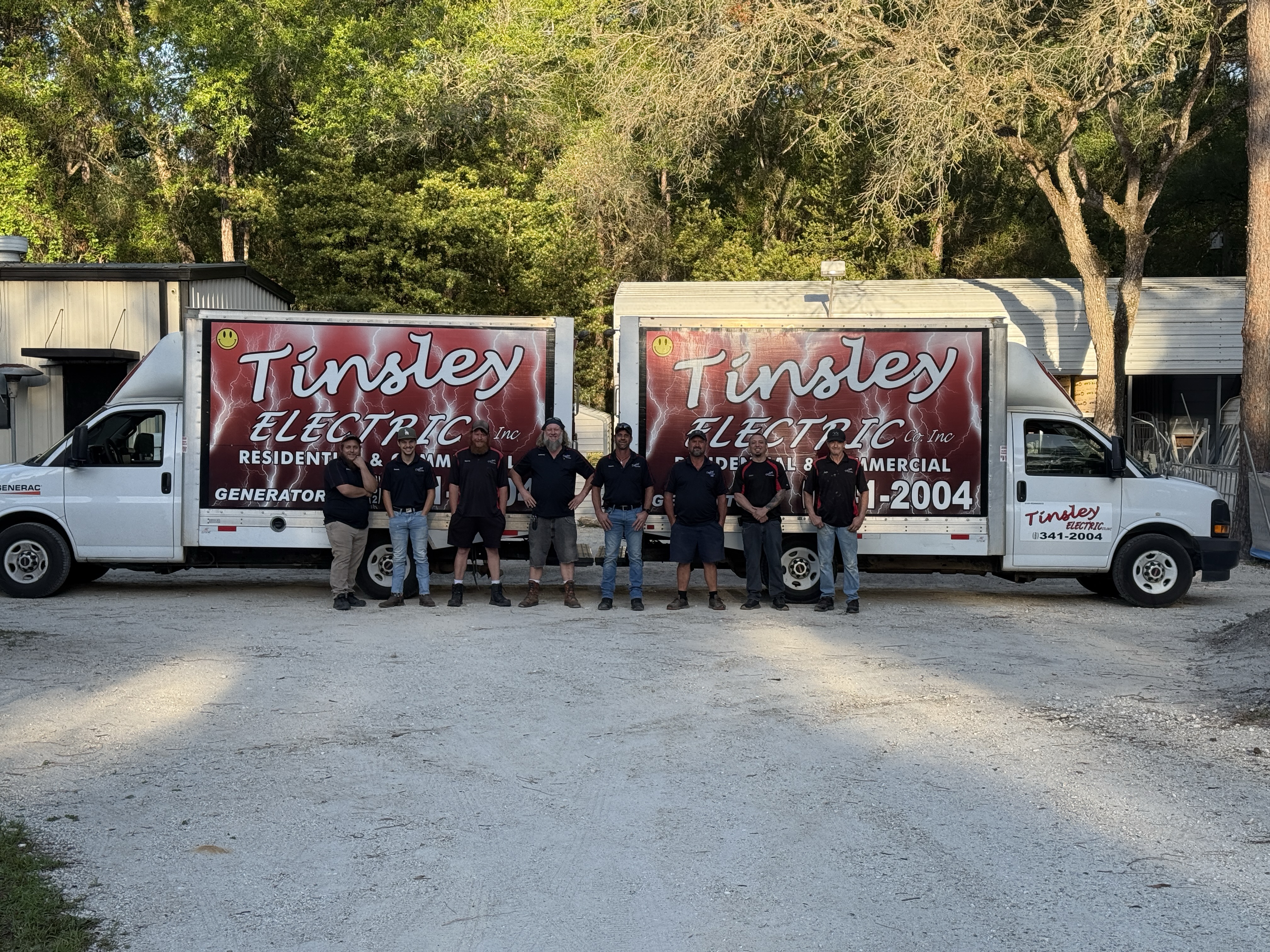 The Tinsley Electric team standing together in front of two branded Tinsley Electric service trucks